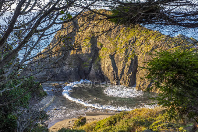 Waves surging through a hole in Arch Rock create an interesting arcing wave, Harris Beach State Park, near Brookings;  Oregon, United States of America — Stock Photo