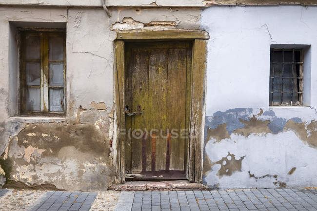 Деревянная дверь и выветриваемая стена на доме; Сеговия, Кастилия и Леон, Испания — стоковое фото