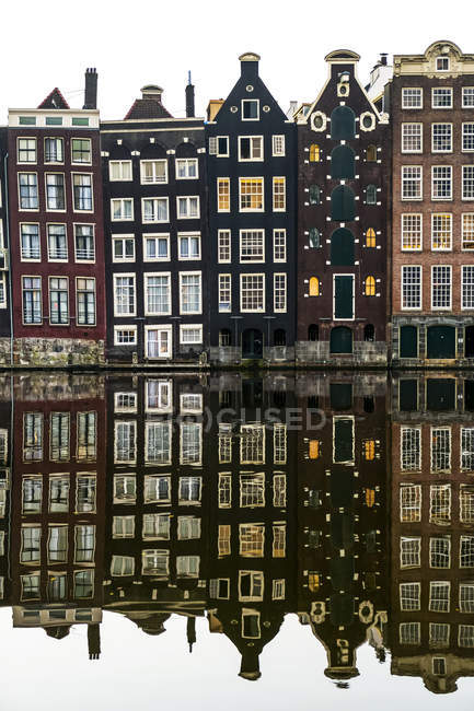 Façades de bâtiments avec un miroir réfléchissant dans un canal ; Amsterdam, Pays-Bas — Photo de stock