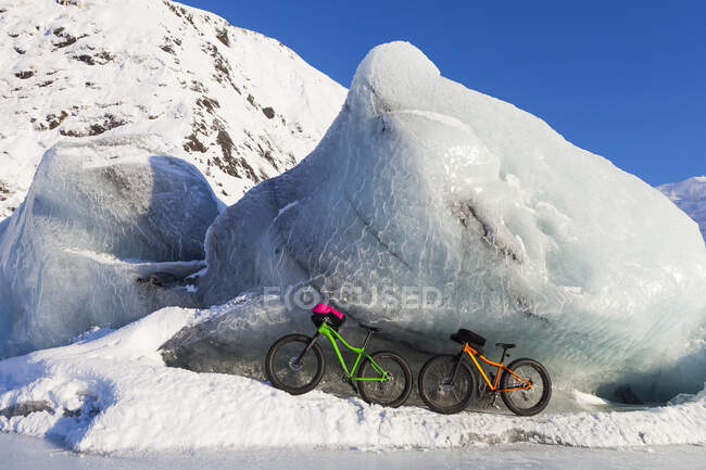 Fatbikes, 907 bicicleta de pneu gordo e Fatback bicicleta de pneu gordo, descansando contra iceberg gigante no inverno em Portage Lake, Chugach National Forest; Portage, Alaska, Estados Unidos da América — Fotografia de Stock