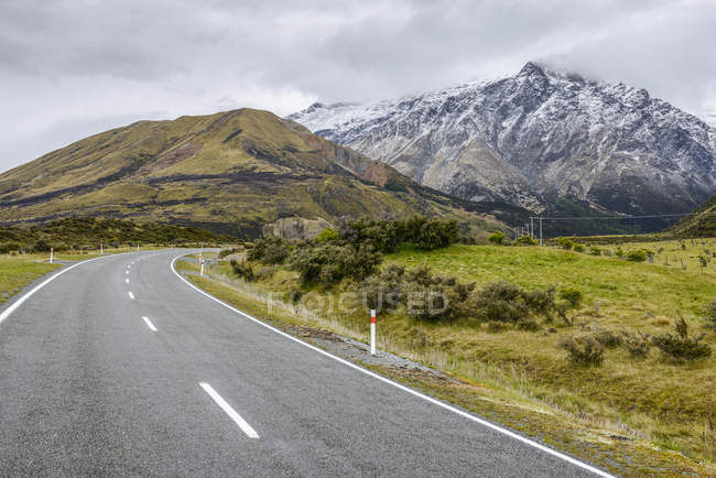 Montañas nevadas y Mount Cook Road; Isla Sur, Nueva Zelanda - foto de stock