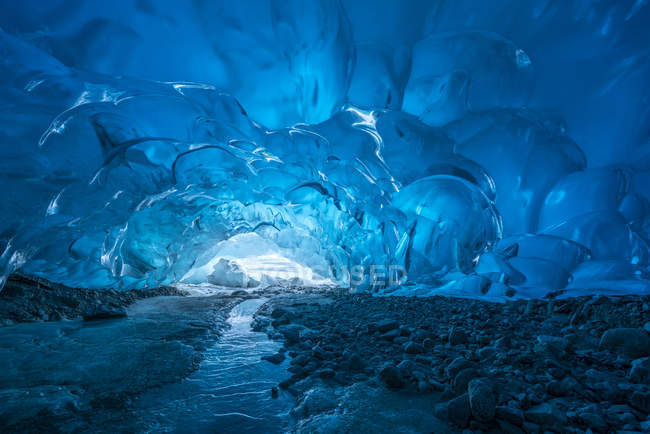 La glace glaciaire bleue est exposée à l'intérieur d'une grotte de glace à l'extrémité du glacier Mendenhall, lac Mendenhall, forêt nationale des Tongass ; Alaska, États-Unis d'Amérique — Photo de stock