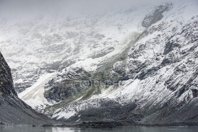 Trace d'avalanche grise sur une pente de montagne enneigée au parc national du Mont-Cook, piste Hooker Valley ; île du Sud, Nouvelle-Zélande — Photo de stock