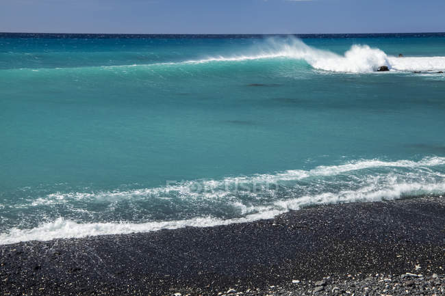 Серфинг на пляже с черным песком, залив Пуэо, побережье Северной Коны; Кайлуа-Кона, остров Гавайи, Гавайи, Соединенные Штаты Америки — стоковое фото