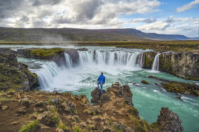 Homem em pé acima da cachoeira Godafoss, Norte da Islândia; Islândia — Fotografia de Stock