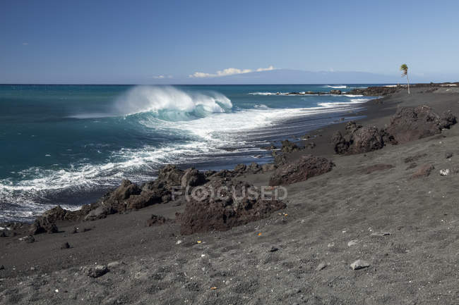 Черный песчаный пляж и волны, ломающиеся у берега, залив Пуэо, побережье Северной Коны; Кайлуа-Кона, остров Гавайи, Гавайи, Соединенные Штаты Америки — стоковое фото