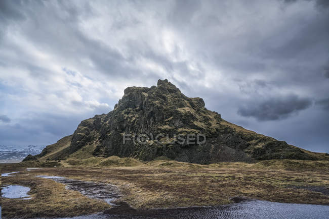 Moody y dramática escena de una pequeña colina a lo largo de la orilla sur de Islandia; Islandia - foto de stock