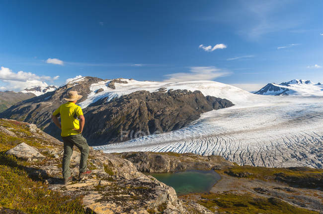 Vista trasera del excursionista con sombrero mirando hacia el Parque Nacional Kenai Fjords, Península de Kenai, Alaska, Estados Unidos de América - foto de stock