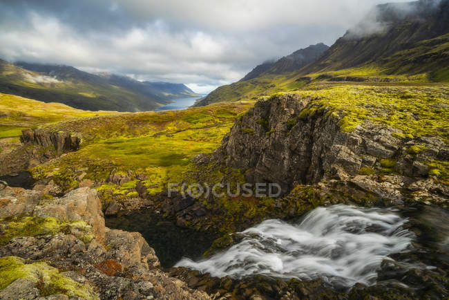 Прочный исландский ландшафт с ярко-зеленой тундрой и видом на побережье вдалеке; Исландия — стоковое фото