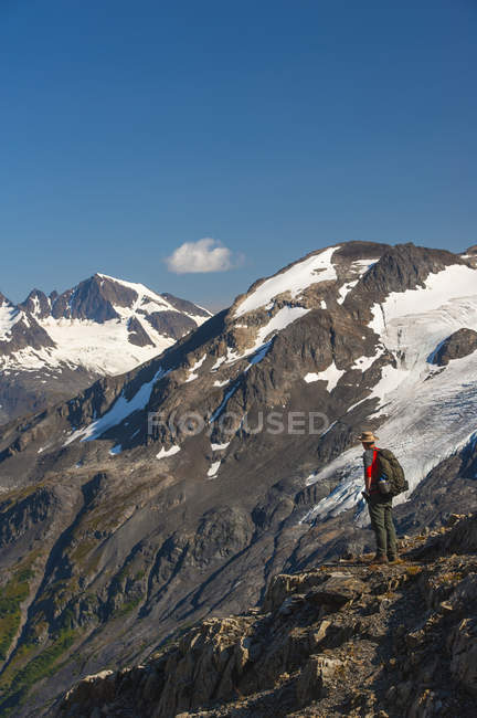 Man hiking near the Harding Icefield Trail with the Kenai Mountains and an unnamed hanging glacier in the background, Kenai Fjords National Park, Kenai Peninsula, South-central Alaska, United States of America — Stock Photo