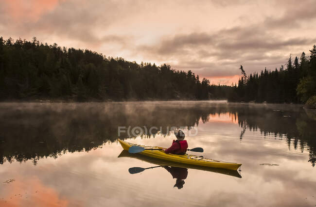 A man kayaking at sunset in the Rushing River, near Kenora; Ontario, Canada — Stock Photo