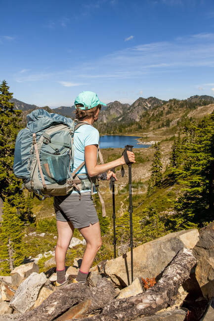 Female backpacker on High Divide Trail pausing to take a look at the view of Lunch Lake in summertime, Seven Lakes Basin, Olympic National Park, Olympic Mountains; Washington, United States of America — Stock Photo