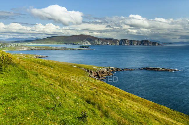Agua azul brillante y exuberante hierba verde a lo largo de la costa de la isla de Achill en la ruta costera del Atlántico; Isla de Achill, Condado de Mayo, Irlanda - foto de stock