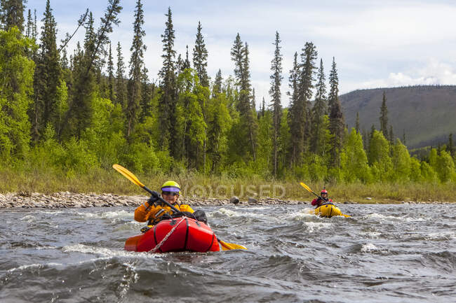Two women packrafters negotiating a tributary of the Charley River in summertime, Yukon Charley Rivers National Preserve; Alaska, United States of America — Stock Photo