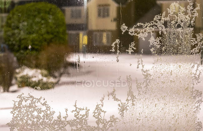 Морозні кристали на житловому вікні з видом на сніжну вулицю і будинки; Південний Шилдс, Тайн і Вір, Англія. — стокове фото