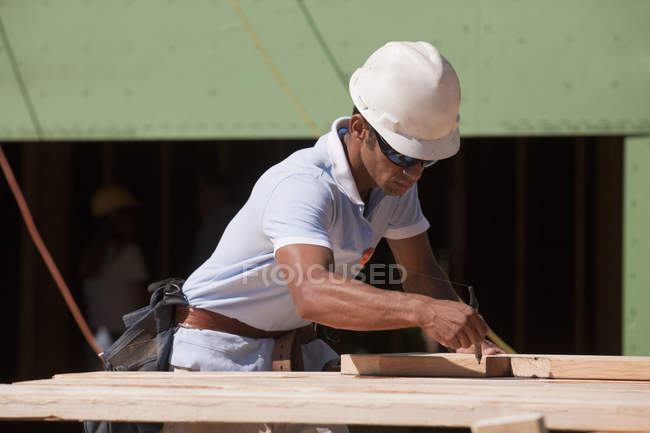Carpinteiro usando triângulo para marcar linha de corte chanfrado na viga — Fotografia de Stock