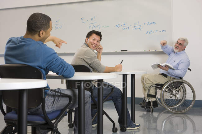 Professeur d'université avec Dystrophie musculaire enseignant aux étudiants dans une salle de classe — Photo de stock