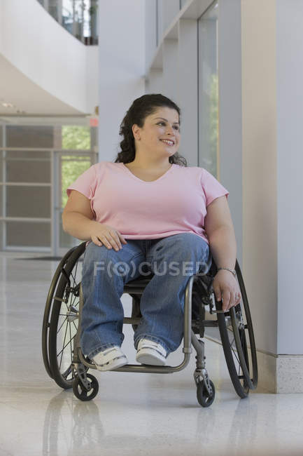 Donna con Spina Bifida seduta su una sedia a rotelle e sorridente — Foto stock