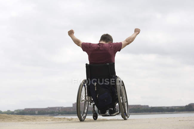 Uomo handicappato su una sedia a rotelle mani alzate — Foto stock