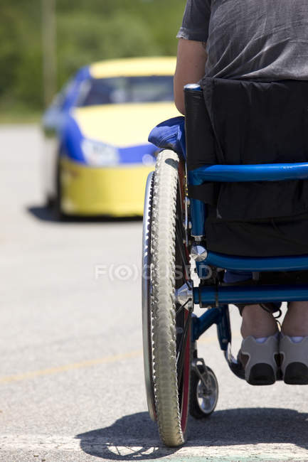 Person im Rollstuhl gegenüber Rennwagen, Rückansicht — Stockfoto