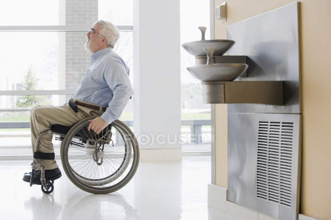 Universitätsprofessor mit Muskeldystrophie im Rollstuhl auf einem Flur — Stockfoto