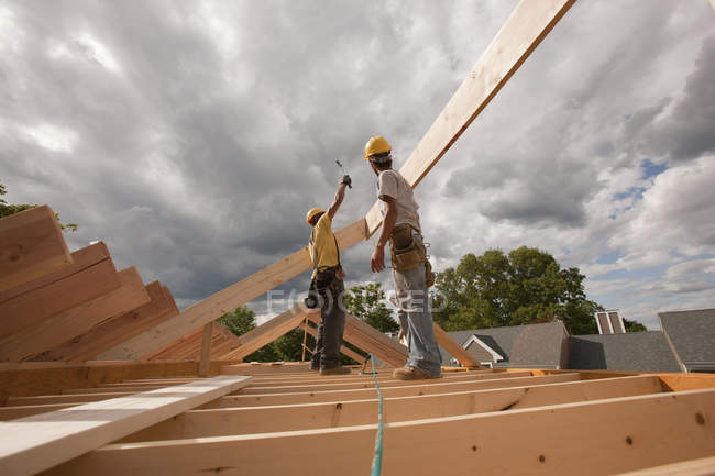 Carpinteiros martelando telhado vigas para transportar — Fotografia de Stock