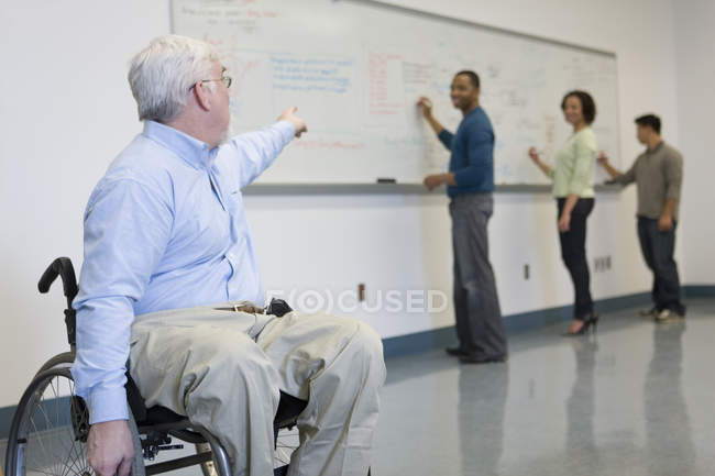 University professor with Muscular Dystrophy teaching students in a classroom — Stock Photo