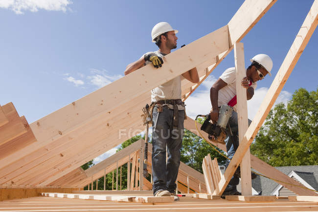 Carpenters aligning roof rafters at building construction site — Stock Photo
