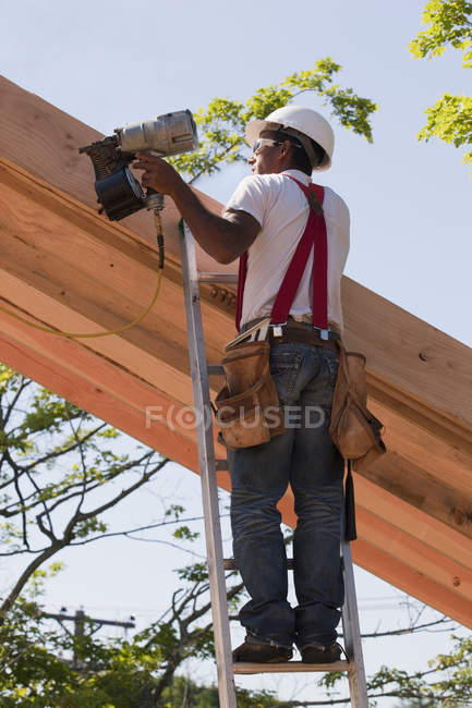 Charpentier clouant des chevrons de toit sur le chantier de construction — Photo de stock