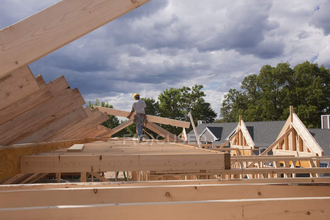 Carpinteiro colocando vigas de telhado no canteiro de obras — Fotografia de Stock