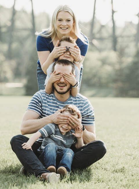 Porträt einer Familie mit kleinen Kindern in einem Park, die in einer Reihe steht und sich gegenseitig die Augen verdeckt; edmonton, alberta, canada — Stockfoto