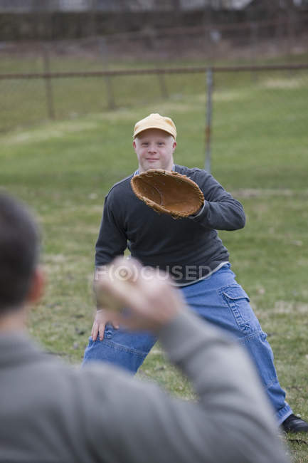 Father and son with Down Syndrome about to play baseball in park — Stock Photo