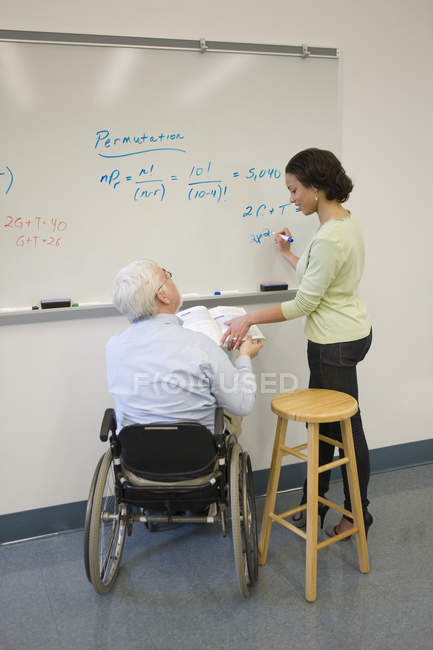 Professore universitario con distrofia muscolare che insegna agli studenti in classe — Foto stock