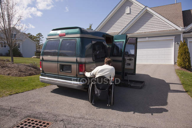Человек с повреждением спинного мозга с помощью намагниченного пульта дистанционного управления, чтобы открыть свой доступный автомобиль — стоковое фото