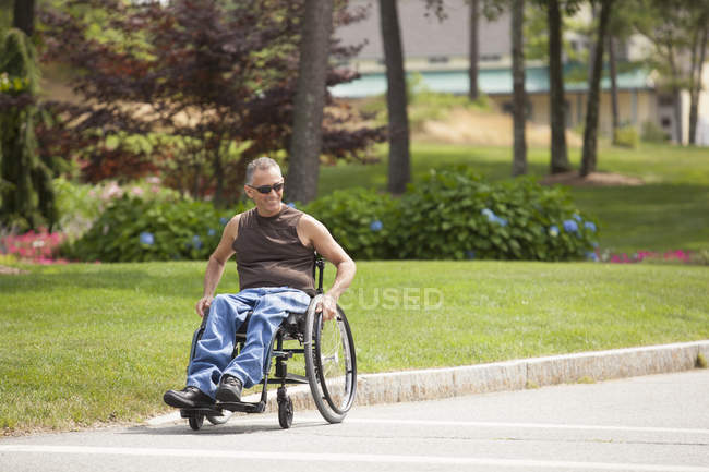 Homme avec blessure à la moelle épinière dans un passage à niveau en fauteuil roulant à pied accessible — Photo de stock