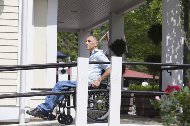 Uomo con lesione del midollo spinale su una sedia a rotelle in cima a una rampa accessibile — Foto stock