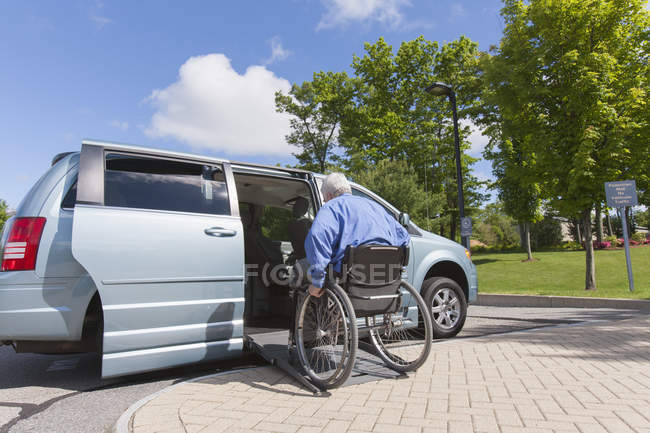 Hombre con distrofia muscular y diabetes subiendo a una furgoneta accesible - foto de stock