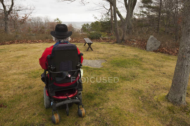 Homme avec sclérose en plaques dans un fauteuil roulant motorisé dans sa cour arrière — Photo de stock