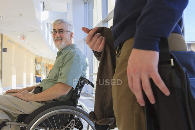 Professeur avec dystrophie musculaire dans un couloir universitaire avec un étudiant — Photo de stock