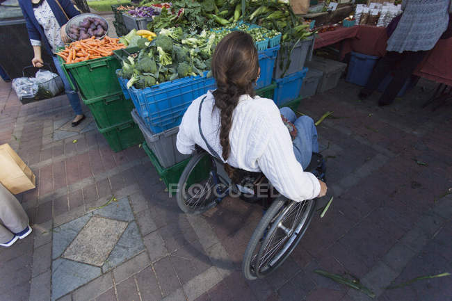 Femme avec lésion de la moelle épinière dans le shopping en fauteuil roulant au marché extérieur — Photo de stock
