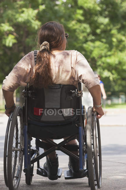 Woman with spinal cord injury crossing street at accessible access — Stock Photo
