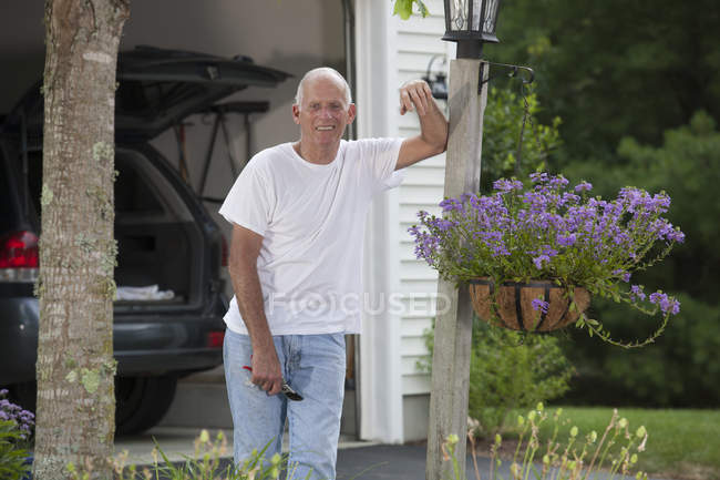 Старший мужчина работает в своем цветочном саду — стоковое фото
