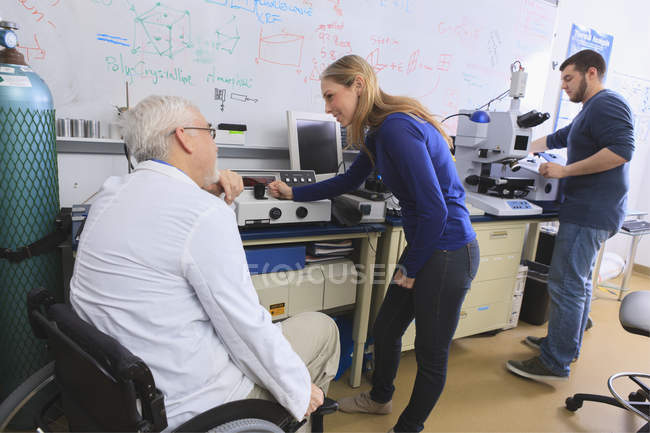 Professore con distrofia muscolare che lavora con gli studenti in laboratorio — Foto stock