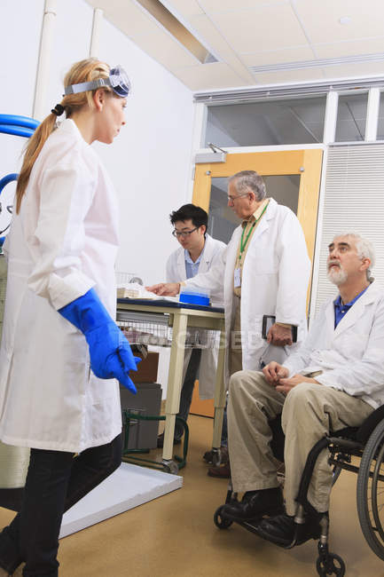 Professor with muscular dystrophy working with students in a laboratory — Stock Photo