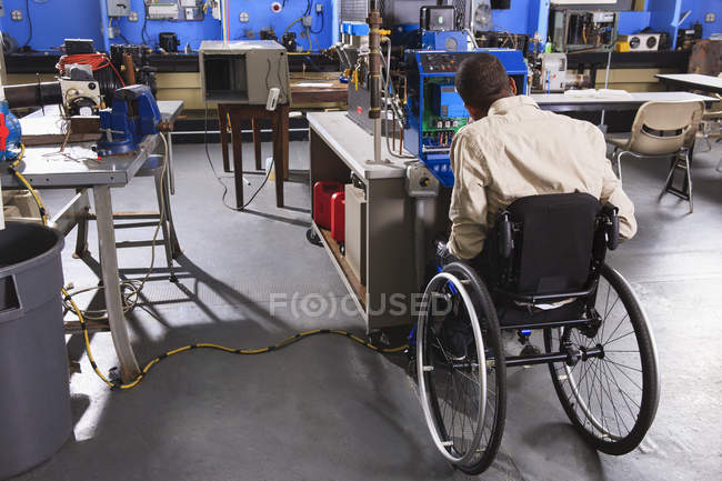 Student in wheelchair studying furnace electronic control system in HVAC classroom — Stock Photo