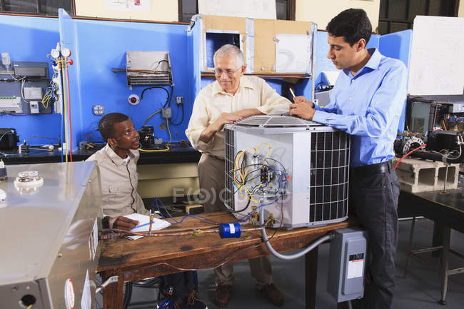 Instructor capacitando a los estudiantes sobre unidades de aire acondicionado en el aula de HVAC - foto de stock