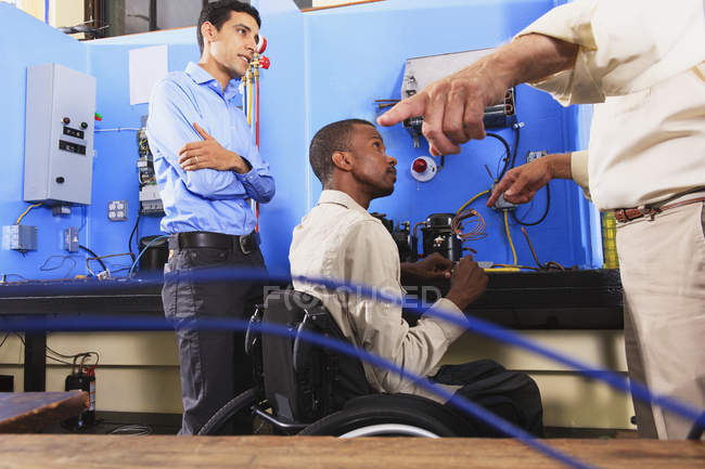 Instructeur discutant bobine de condenseur sur l'unité de réfrigération avec l'étudiant en fauteuil roulant — Photo de stock