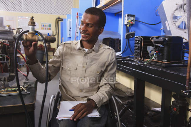 Studente in sedia a rotelle che esamina le valvole di controllo del carburante sul forno in classe HVAC — Foto stock