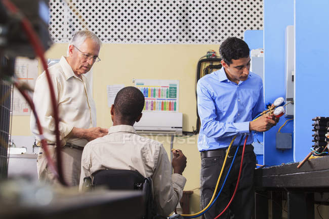 Étudiant démontrant le collecteur de recharge du climatiseur avec des jauges dans la salle de classe CVC — Photo de stock