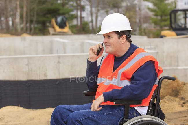 Construction engineer with spinal cord injury on radio at foundation site — Stock Photo